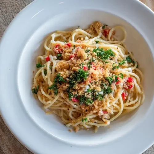 Spaghetti mit Knoblauch, Chili, Petersilie und gerösteten Brotkrumen, angerichtet auf weißem Teller
