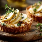 Ziegenkäse-Tartlet mit Feigensenf, Birne, Walnuss und Honig auf rustikalem Teller