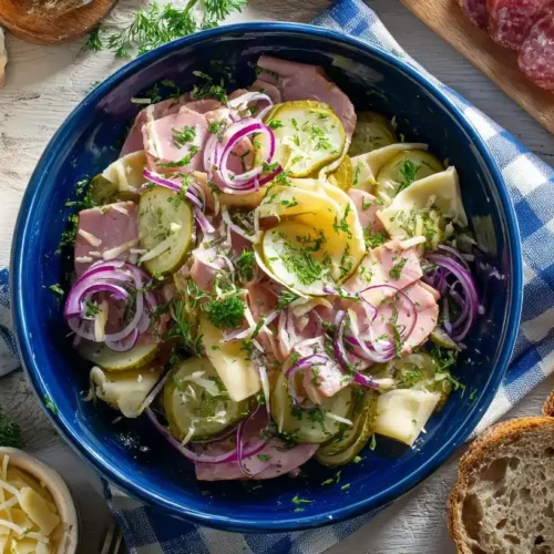 Frisch zubereiteter Schweizer Wurstsalat mit Käse in einer Salatschüssel, garniert mit Petersilie