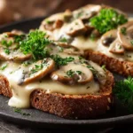 Zwei Scheiben Vollkorntoast mit cremiger Pilz-Käse-Soße und Petersilie garniert